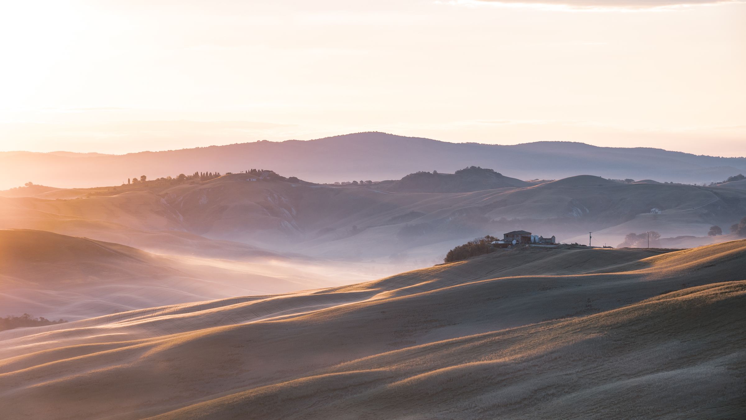 Soft dawn light and layers of mist across the rolling hills of the Crete dell’Orcia in Tuscany