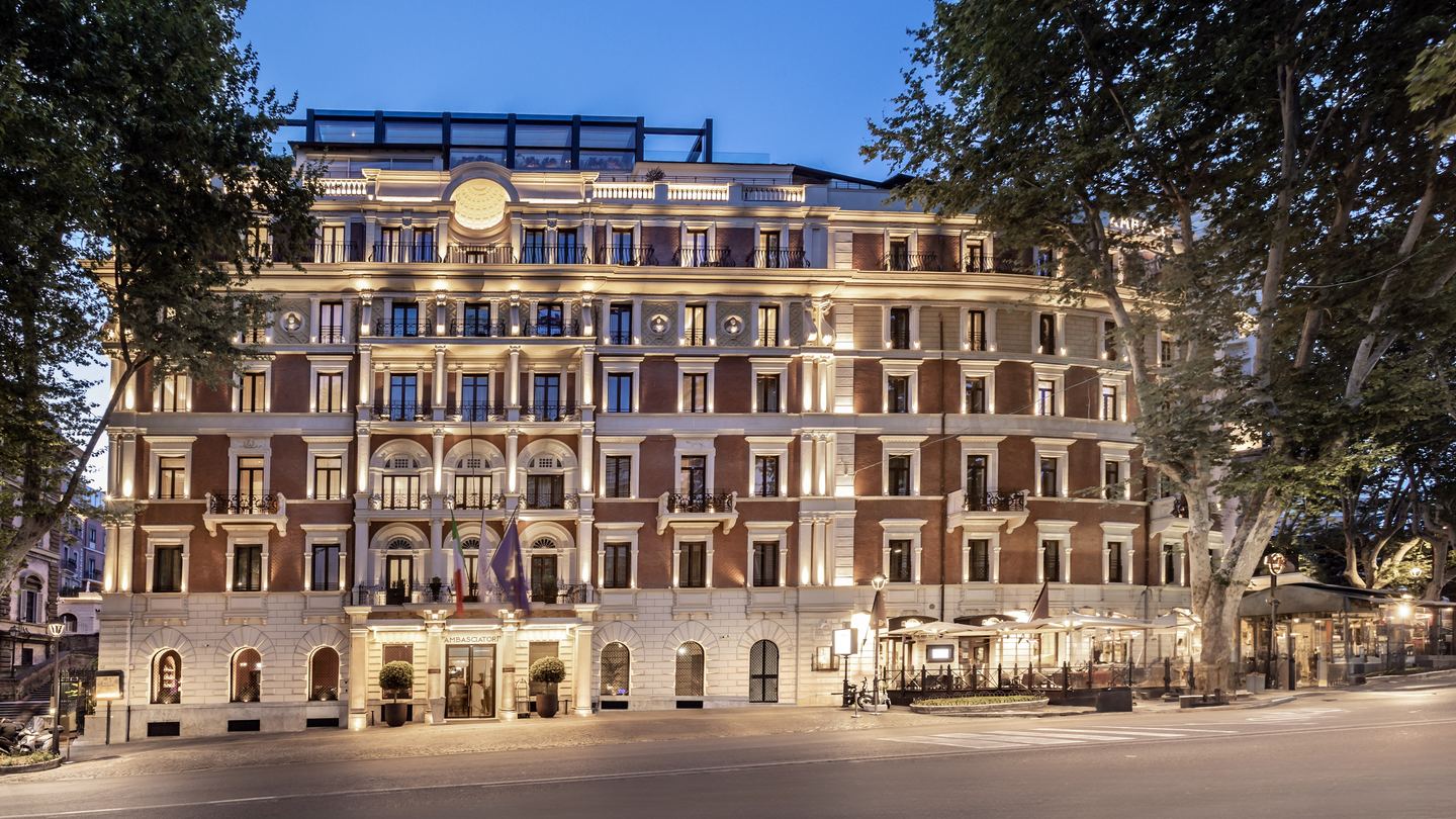 An illuminated hotel facade in Rome at dusk