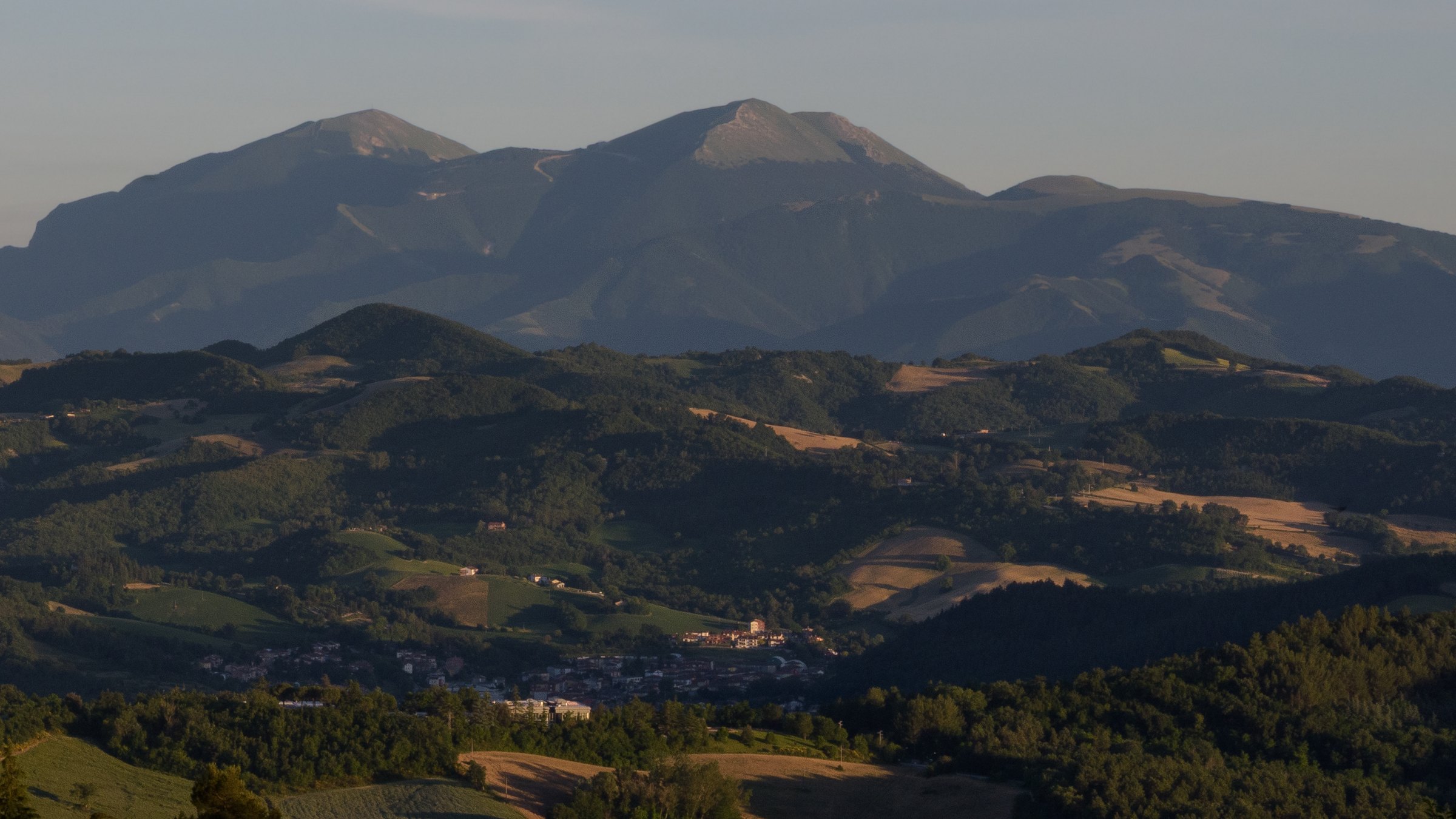 Late sunlight across wooded hills and layered mountains south of Urbino in Le Marche