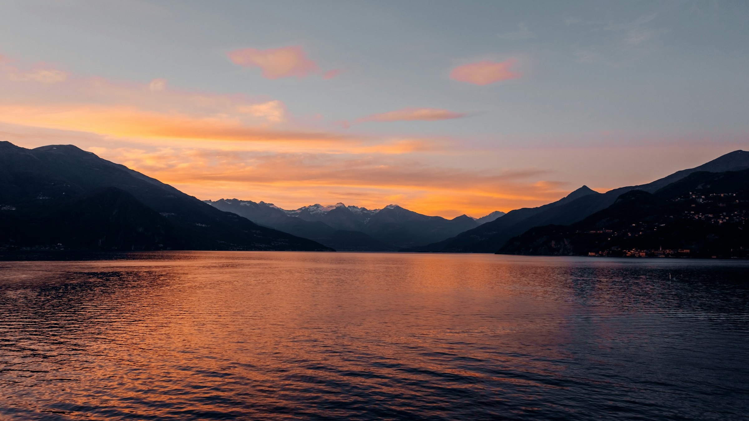 Peach sunset reflected on Lake Como between dark mountain silhouettes