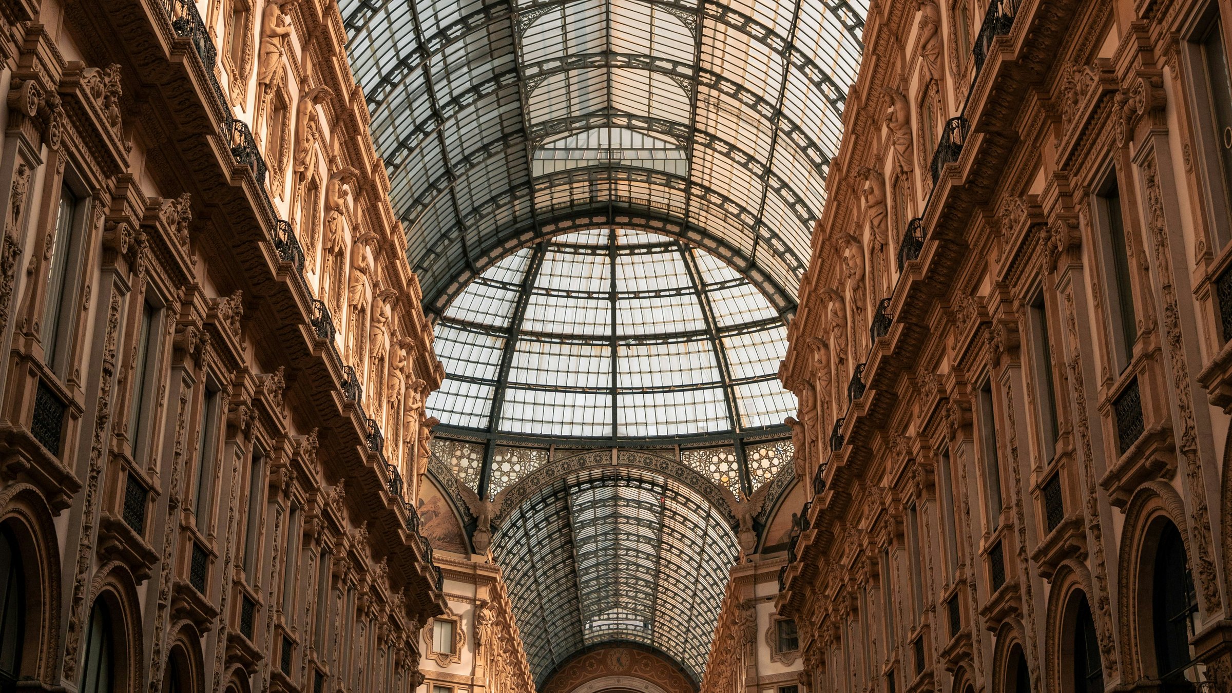 Warm light on the ornate walls and receding glass vault of Milan's Galleria Vittorio Emanuele II