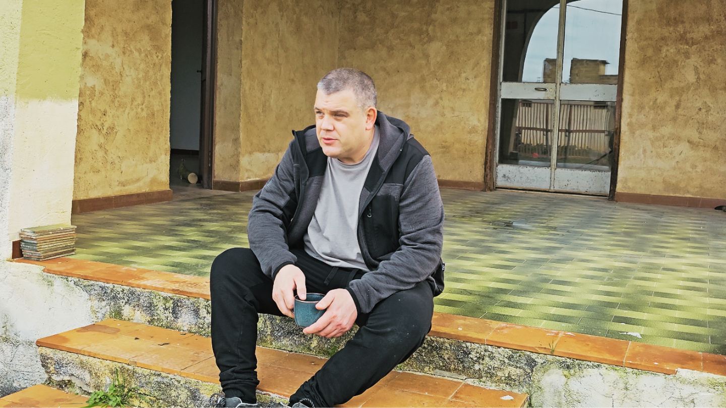 Jonathan Smith seated on the steps of the villa documented by Operation Sicily
