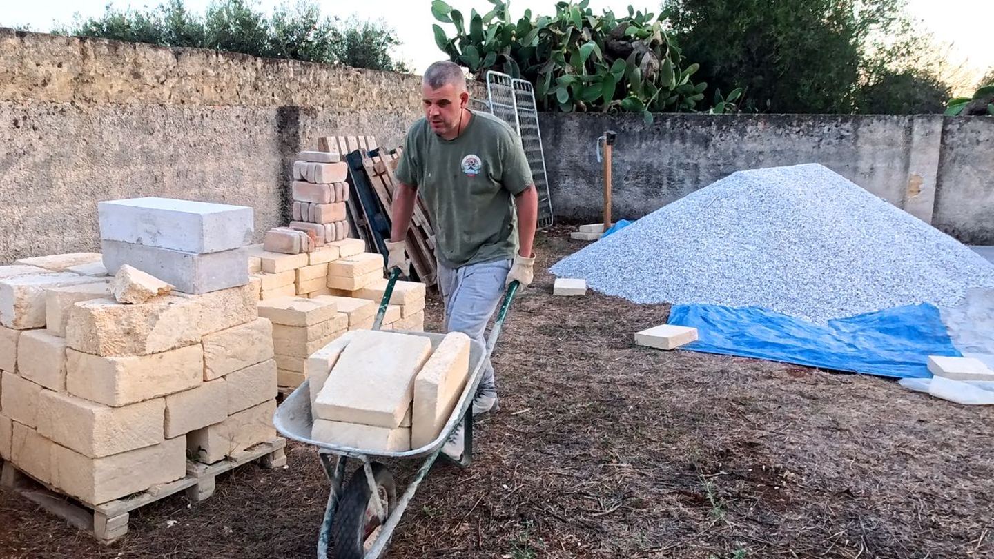 Jonathan Smith moving pale stone blocks in a wheelbarrow during work at the Sicilian villa