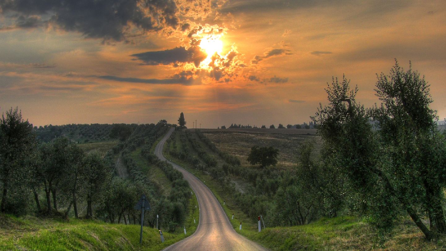 A winding country road through the Crete Senesi at sunset